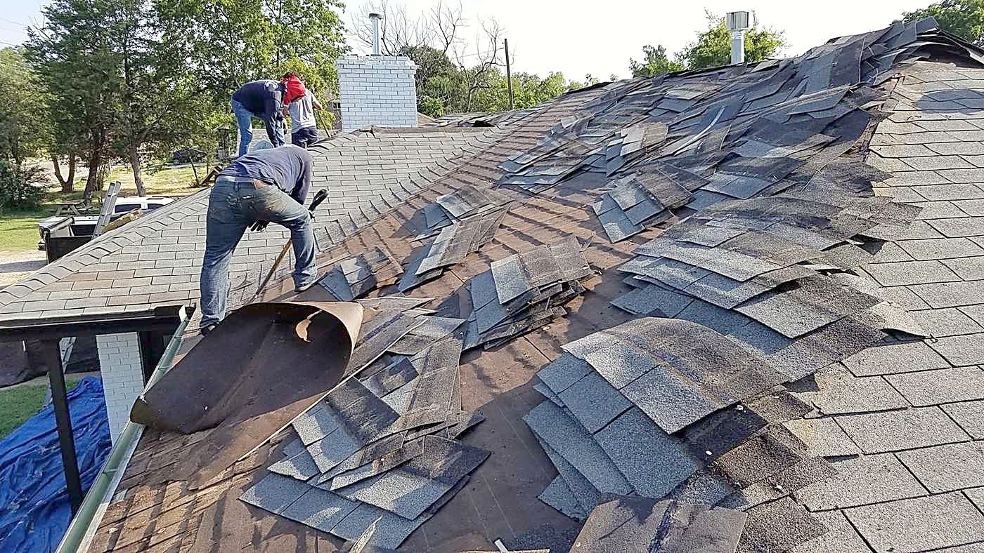A crew member rolling underlayment out across a stripped roof