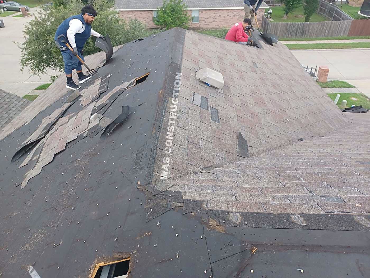 Old shingles torn back across a roof slope with the felt showing