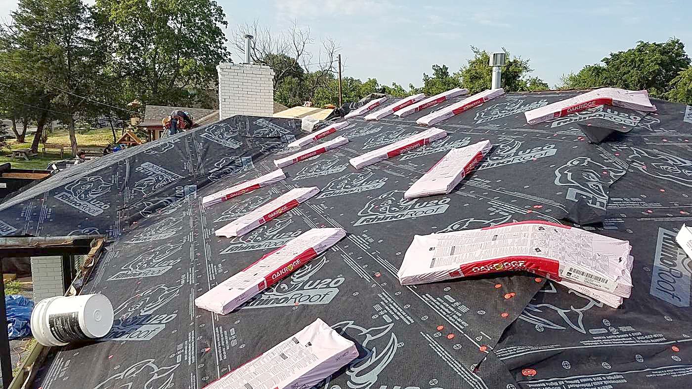 Shingle bundles staged in rows over fresh underlayment